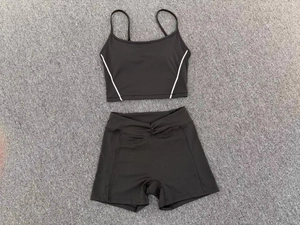 Flat lay of black two-piece sports set featuring a crop top and criss-cross waist shorts