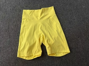 Détail du short de yoga jaune taille haute avec coutures plates sur fond gris