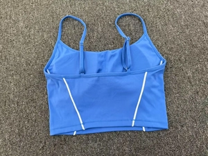 Flat lay of blue yoga tank top featuring white contrast piping and adjustable straps