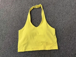 Dettaglio del reggiseno yoga giallo acceso con fibbia regolabile su tessuto grigio