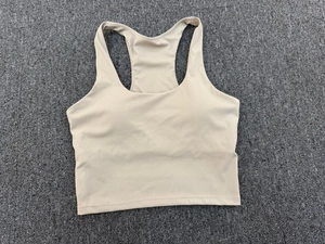 Detailansicht eines beigen Yoga-Tanktops mit Rundhalsausschnitt und Ringerrücken auf grauem Grund