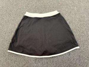 Vue à plat d'une jupe de tennis noire avec bordure blanche et tissu extensible