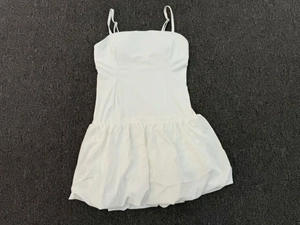 Flat lay of white sleeveless tennis dress with adjustable straps and bubble hem detail
