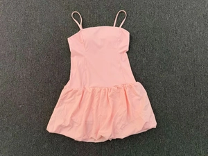 Detailed top view of pink sleeveless bubble hem tennis dress on a textured gray carpet