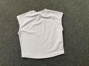 Flat lay macro view of the white slim fit yoga top on a gray textured background