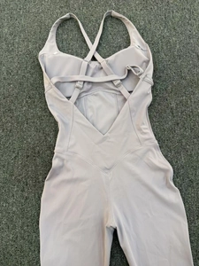 Detail of cross-back straps and adjustable metal buckles on light purple yoga bodysuit