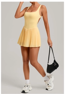 Detail of light yellow backless tennis dress showing pleats and stretch fabric on a model