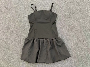 Flat lay of a black sleeveless tennis dress with spaghetti straps and puff hem detail