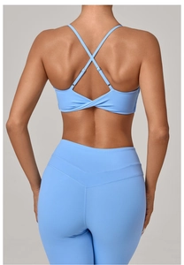 Detail view of sky blue yoga bra with cross straps and high waist leggings with V-seam