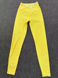 Detailed view of yellow high-waisted yoga leggings with white V-cross waistband trim