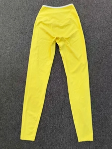 Detail of high waist bright yellow yoga leggings with white contrast waistband on dark rug