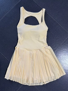Flat lay of yellow backless tennis dress with teardrop cutout and pleated hem