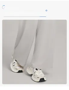 Detail view of light grey wide-leg trousers with high drape and white sneakers
