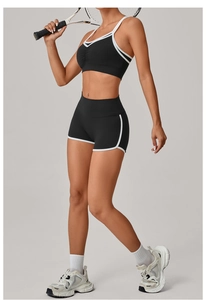 Detail eines zweiteiligen Fitness-Sets mit weißer Paspelierung an Sport-BH und Shorts