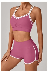 Detail des lila Yoga-Sets mit weißen Paspeln und V-Ausschnitt Sport-BH sowie kurzen Shorts