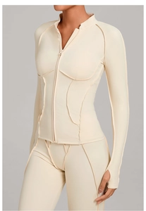 Détail du haut de yoga blanc crème avec coutures overlock et manches avec passe-pouce