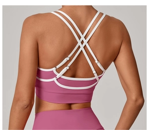Détail du soutien-gorge de sport rose avec sangles croisées blanches et boucles métalliques