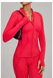Détail de veste de sport rouge avec passe-pouces, col montant zippé et coutures ajustées