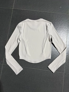 Detail of high-stretch sports top back view with round neck and curved hem in beige grey