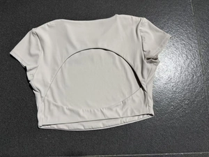 Dettaglio del top da yoga grigio chiaro con schiena aperta e ritaglio circolare sul retro