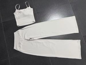 Flat lay of cream yoga set showing rib-knit cropped tank top and high-waisted wide-leg pants