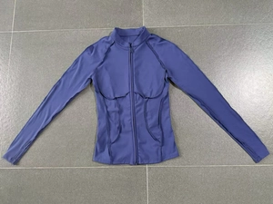 Détail de la veste de yoga montrant les zips invisibles aux poignets et les coutures courbées