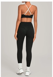 Close-up of peach-lift seam on black high-waist yoga leggings with white cross-back sports bra