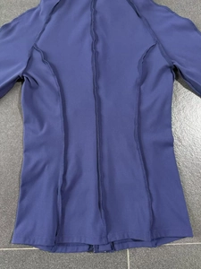 Détail des coutures plates sur le tissu extensible de la veste de yoga bleu foncé