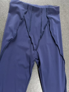 Detail view of deep purple yoga flared pants showing V-shaped stitching and layered cut fabric