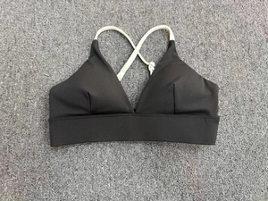 Detail verstellbarer weißer Kreuzträger an einem schwarz-weißen Sport-BH für Yoga