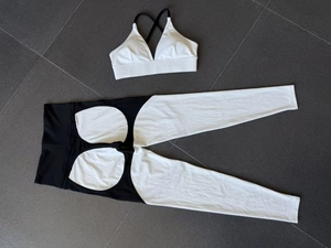 Flat lay detail of a black and white two-piece yoga set with cross straps and high waist pants
