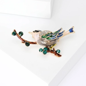 Détail de la broche oiseau en émail coloré avec cristaux et pierres gemmes vertes