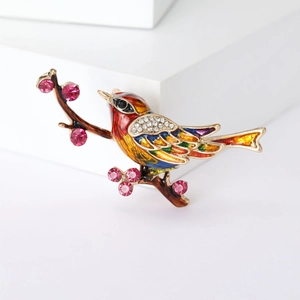 Élégante broche pie avec émail coloré et strass brillants sur une petite branche