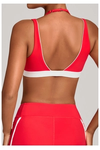 Vue détaillée du dos d'un soutien-gorge de yoga rouge avec liserés blancs et dos en V