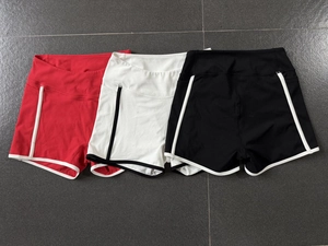 Vue à plat de trois shorts de yoga taille haute en rouge, blanc et noir avec bordures contrastées