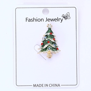 Détail d'une broche sapin de Noël en émail vert ornée de strass colorés sur carte
