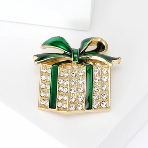 Macro shot of Christmas gift box brooch with green enamel bow and sparkling rhinestones