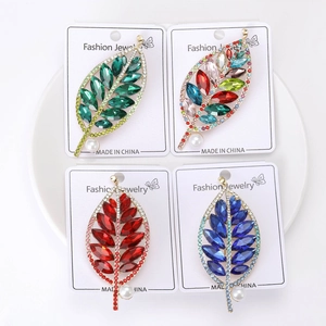 Dettaglio di quattro spille a foglia con cristalli colorati e perle bianche