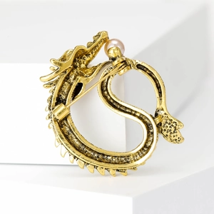 Vintage gold dragon brooch with pearl detail and pin fastener on white display stand
