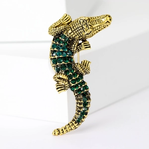 Detailansicht einer Vintage-Krokodilbrosche mit goldenen Schuppen und grünen Kristallen