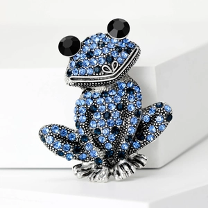 Vue macro d'une broche grenouille 3D avec cristaux bleus et yeux en pierres noires
