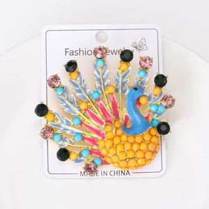 Détail d'une broche paon colorée avec des strass vibrants sur une carte à bijoux