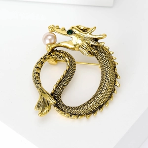 Detail of vintage golden dragon brooch featuring fine scales and a pink pearl