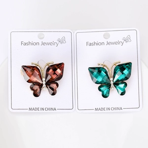 Detail view of crystal butterfly brooches in red and green on display cards