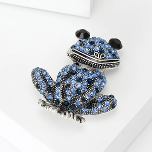 Vue macro d'une broche grenouille avec strass bleus et yeux en pierres précieuses noires