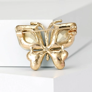 Exquisite golden butterfly brooch featuring green gemstones and starry back pattern detail