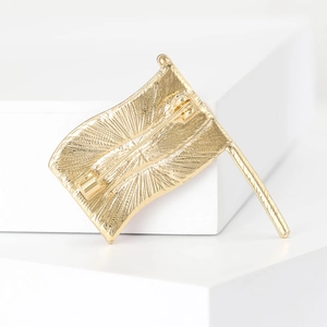 Back view of a gold flag brooch with radial texture and secure rotating pin fastener