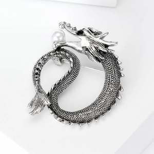 Vintage silver dragon brooch with white pearl and black gemstone on white display stand