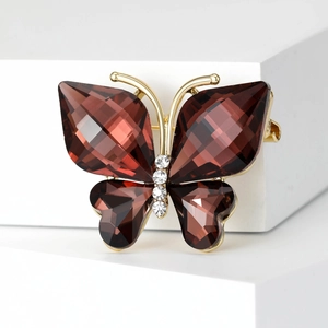 Exquisite crystal butterfly brooch with deep brown wings and golden frame on a white block