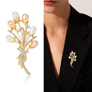 Broche bouquet dorée élégante avec perles et cristaux sur le revers d'un costume noir